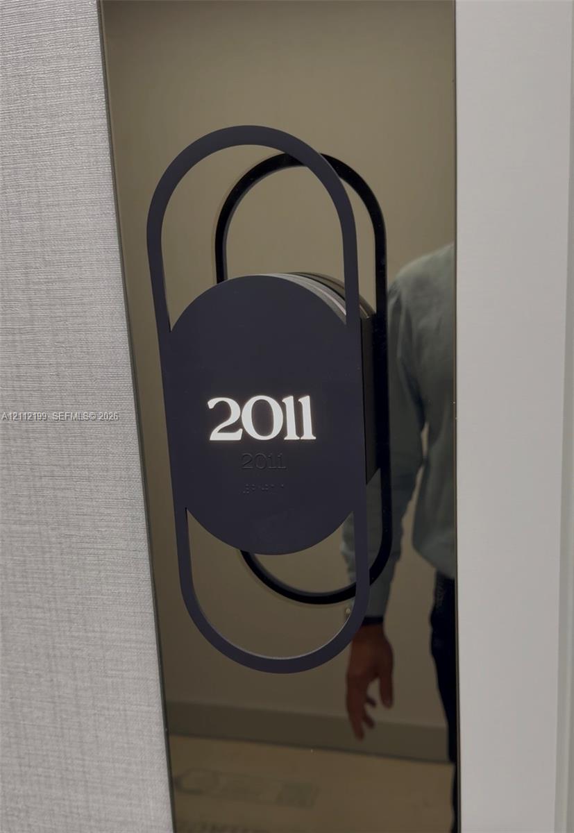 Modern metallic door plaque featuring a matte black geometric frame and integrated Braille signage Modern metallic door plaque featuring a matte black geometric frame and integrated Braille signage
