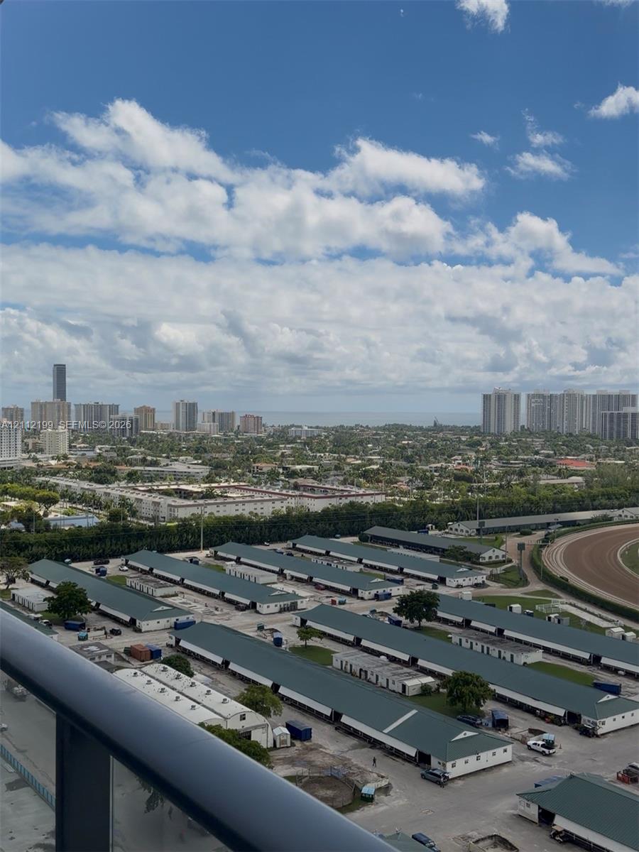 Elevated balcony railing with a panoramic outlook featuring city high-rises, expansive horizon, and racetrack grounds Elevated balcony railing with a panoramic outlook featuring city high-rises, expansive horizon, and racetrack grounds