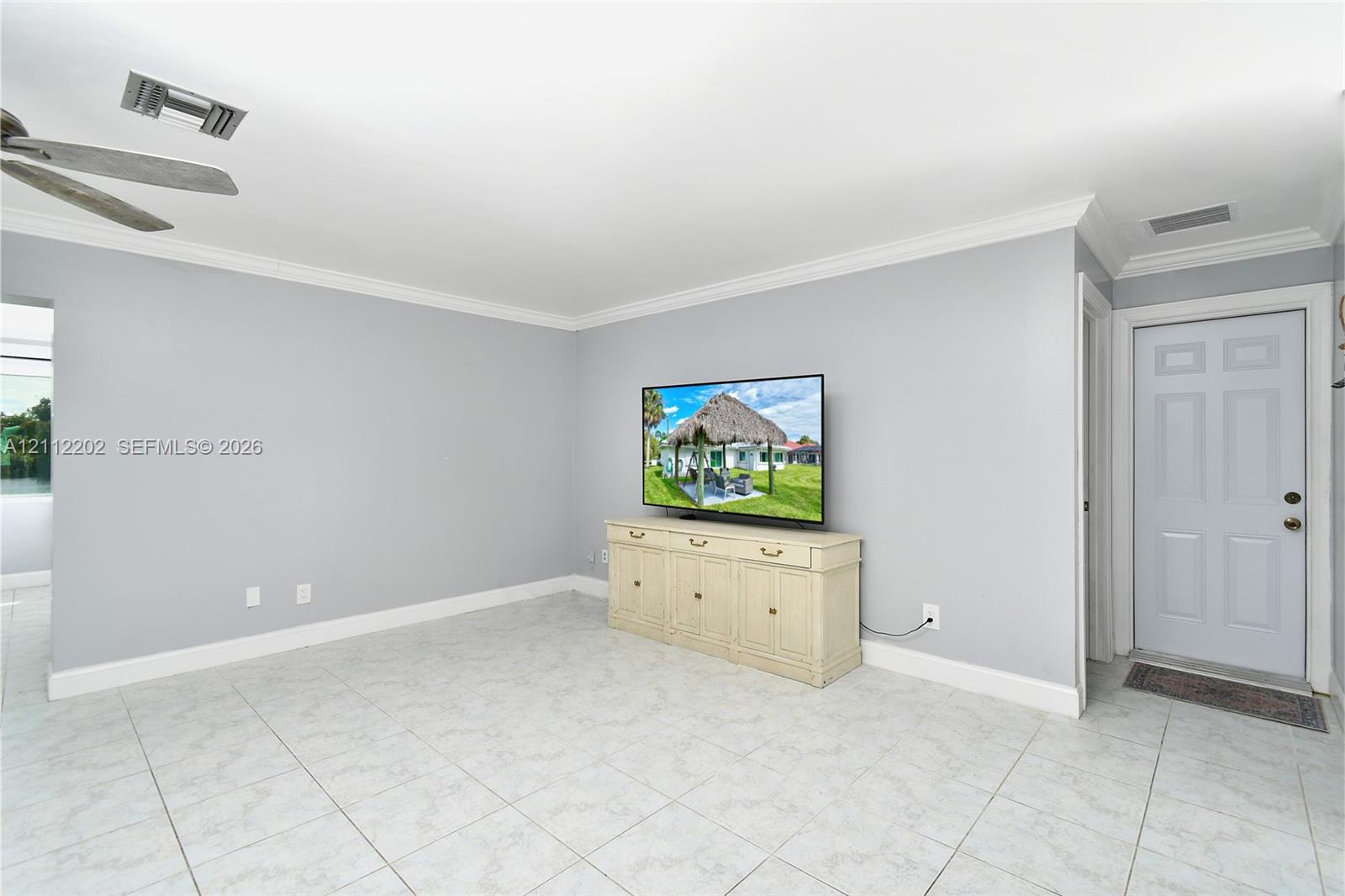 Interior space featuring light-toned tile flooring, crown molding, and a ceiling fan with integrated lighting