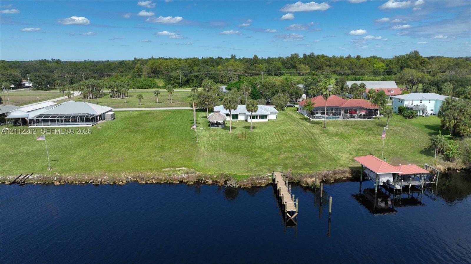 Waterfront property featuring extensive lawn space, a private dock, and a boat lift