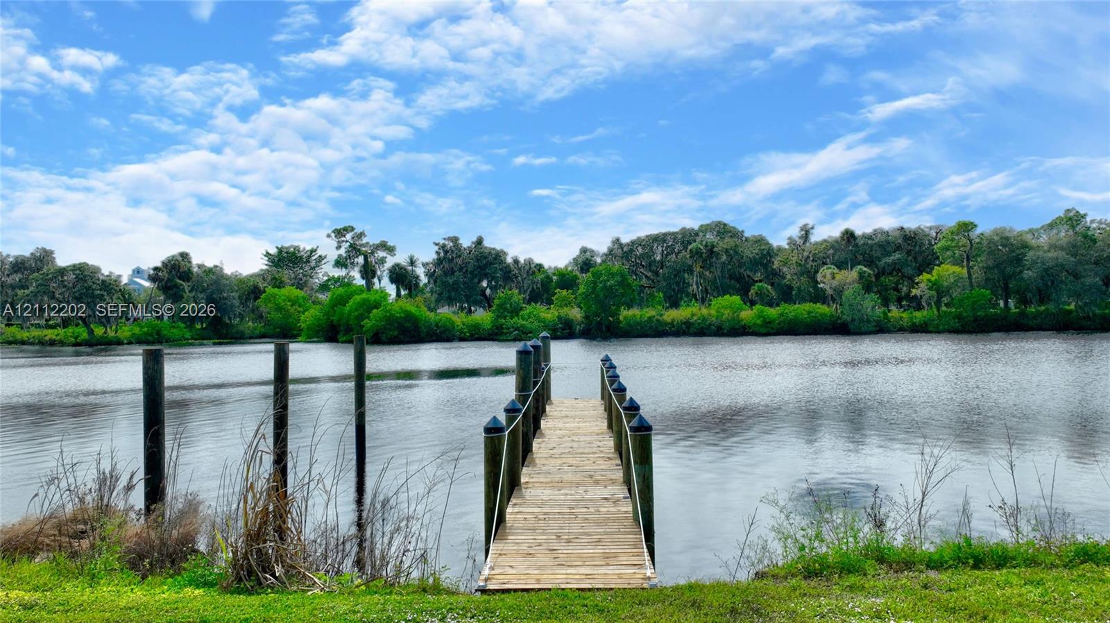 Private wooden dock featuring pilings, rope railings, and direct access to a natural water feature surrounded by mature tree lines