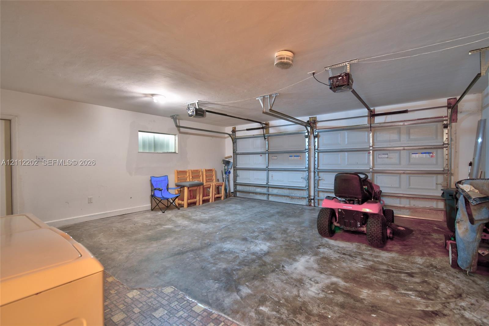 Two-car garage featuring dual overhead metal doors, reinforced ceiling-mounted automatic door openers, and concrete flooring
