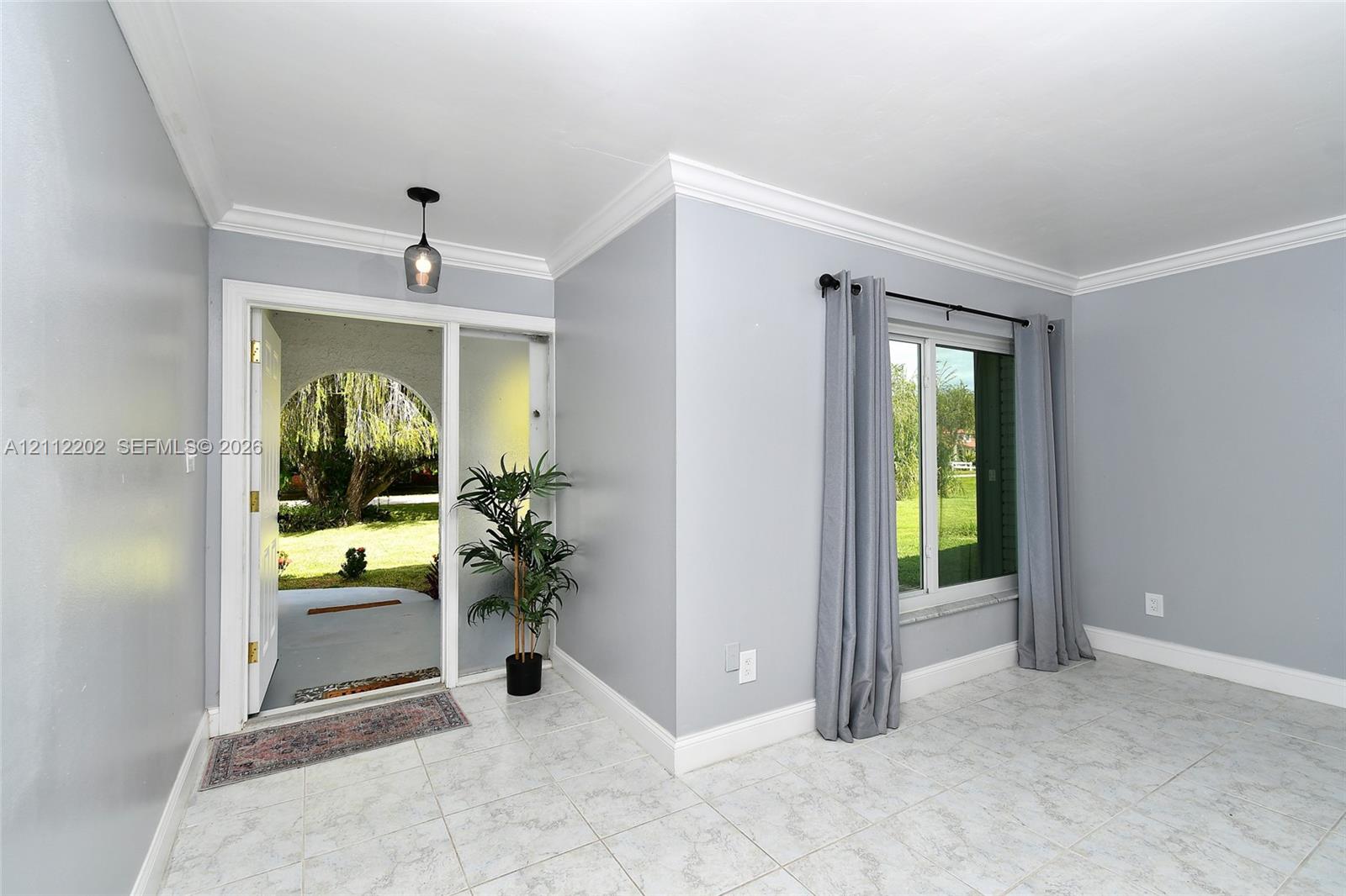 Foyer featuring tile flooring, crown molding, and a decorative pendant light