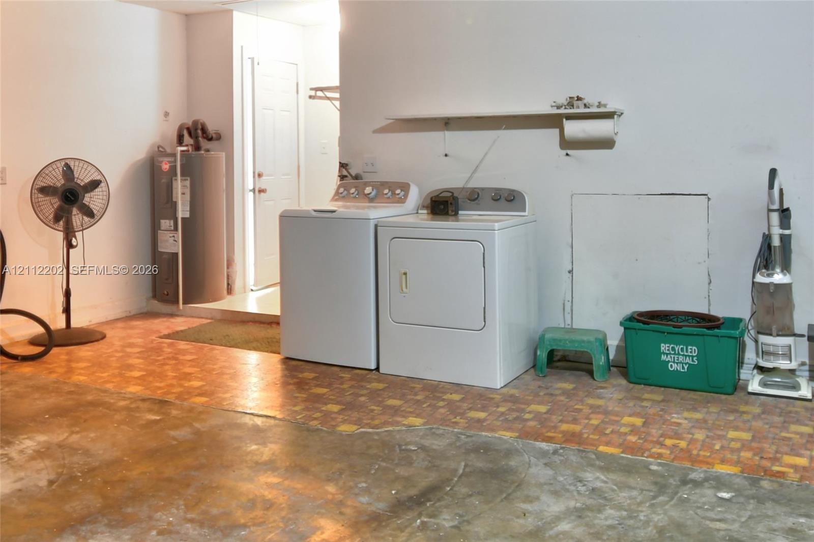 Utility area featuring a tiled floor, wall-mounted storage shelf, and dedicated water heater