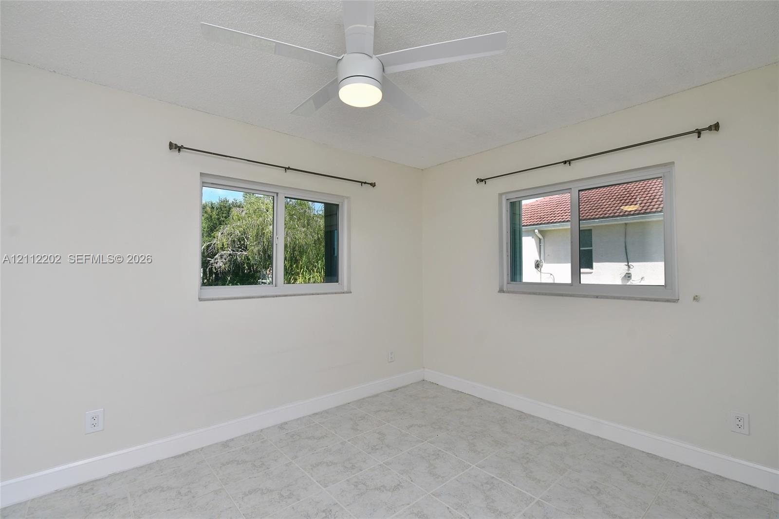 Room featuring neutral wall paint, tile flooring, and a ceiling-mounted light fixture with a fan