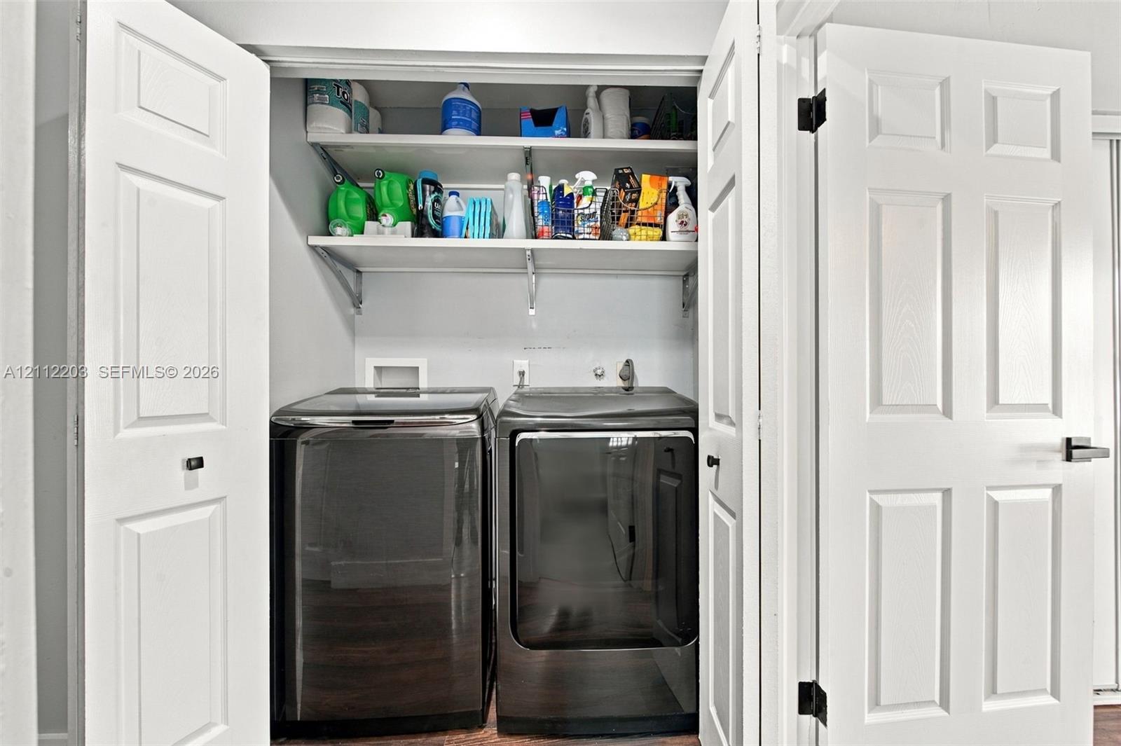 Laundry closet featuring white six-panel bi-fold doors and two tiered built-in storage shelves