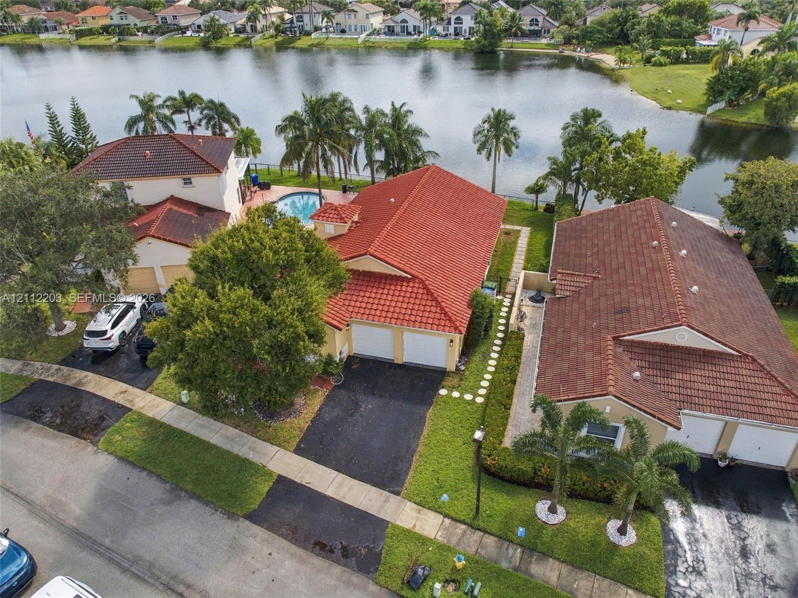 Waterfront property featuring a red tile roof, two-car garage, and in-ground swimming pool