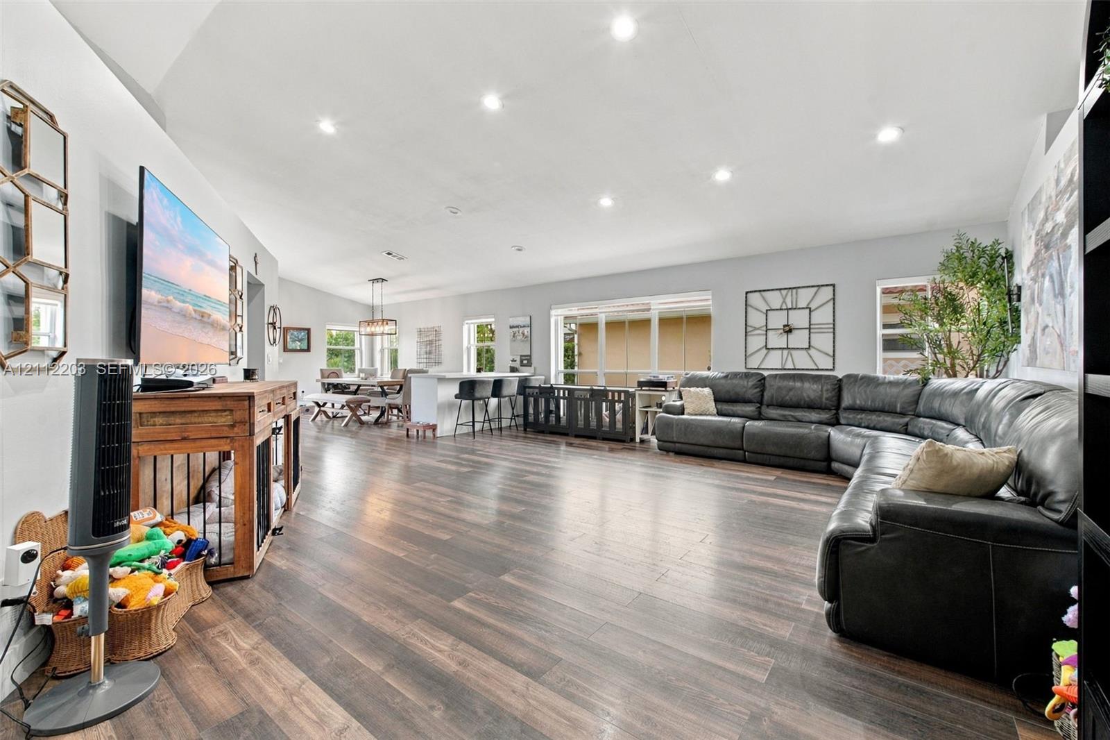 Open-concept room featuring wood-finish flooring, vaulted ceilings, recessed lighting, and large windows