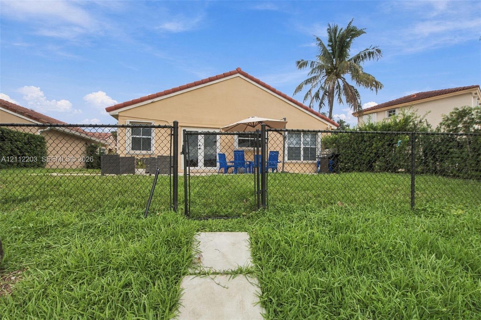 Fenced backyard featuring a concrete walkway, exterior glass paneled doors, and a tile roof