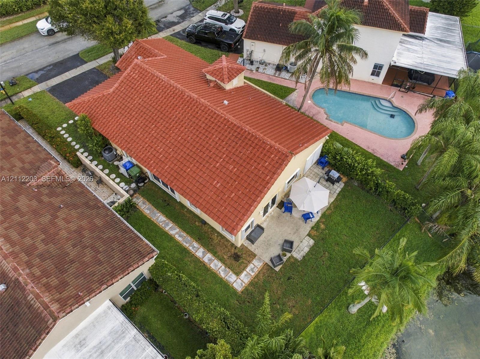 Tile roof construction featuring a central cupola, exterior concrete patio, and fenced backyard landscaping