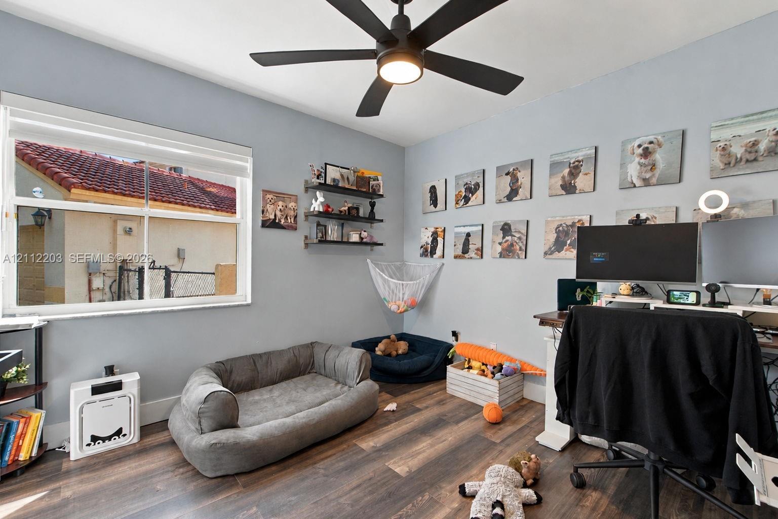 Wood-finish flooring, matte black ceiling fan with integrated lighting, and dual-pane window