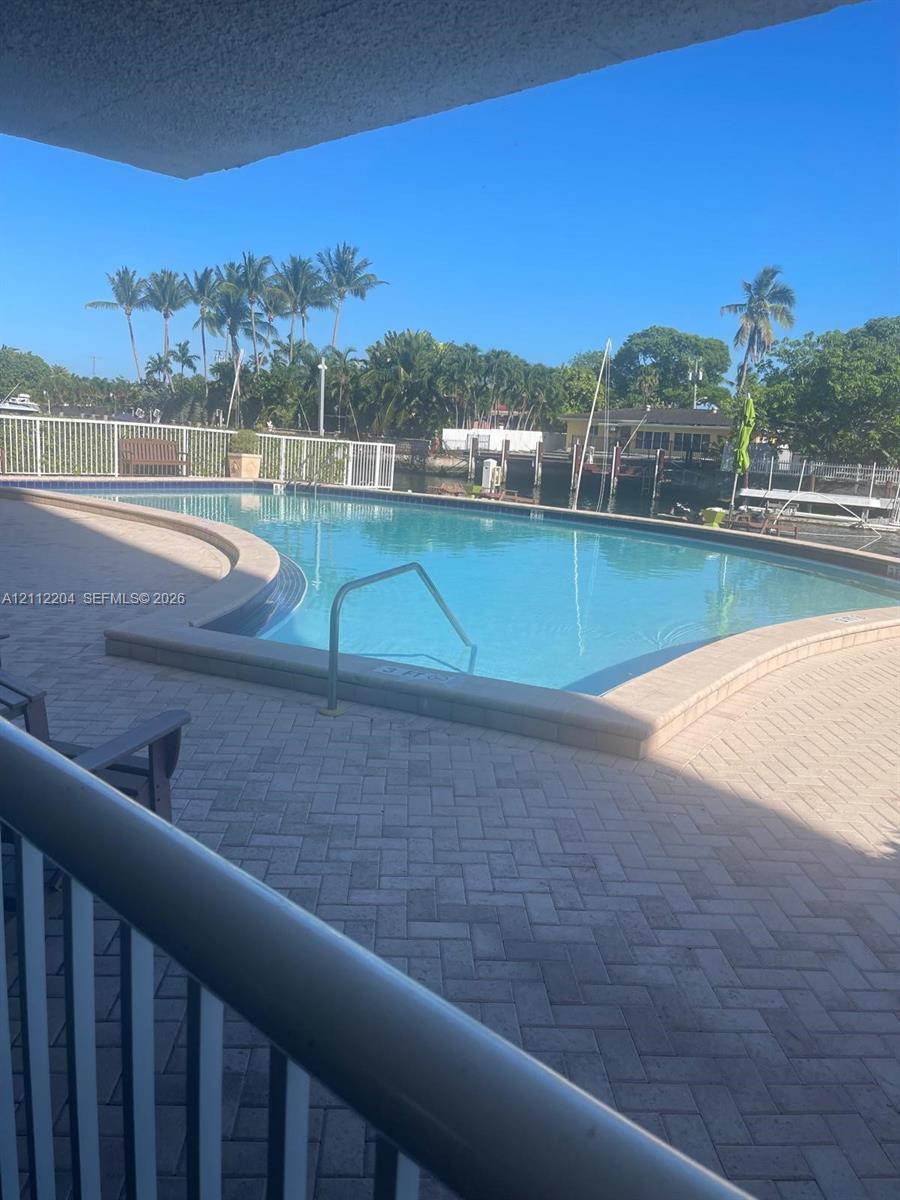 Swimming pool featuring a herringbone-patterned paver deck, metal safety railing, and integrated water access steps