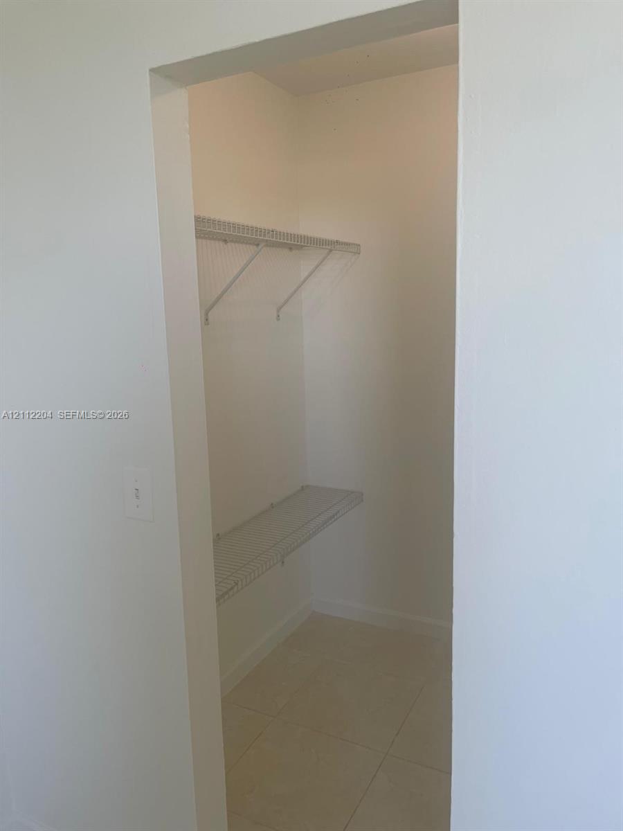 Walk-in closet featuring light-colored tile flooring and two-tier wire shelving