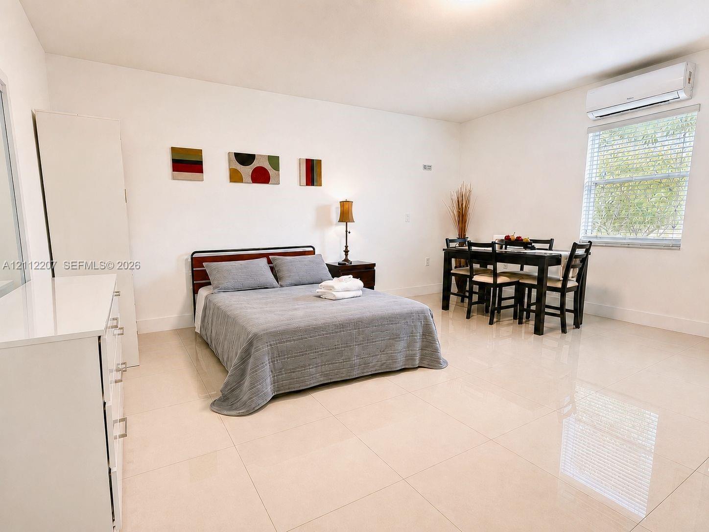 Room featuring neutral tile flooring, white wall finishes, and a wall-mounted ductless air conditioning unit