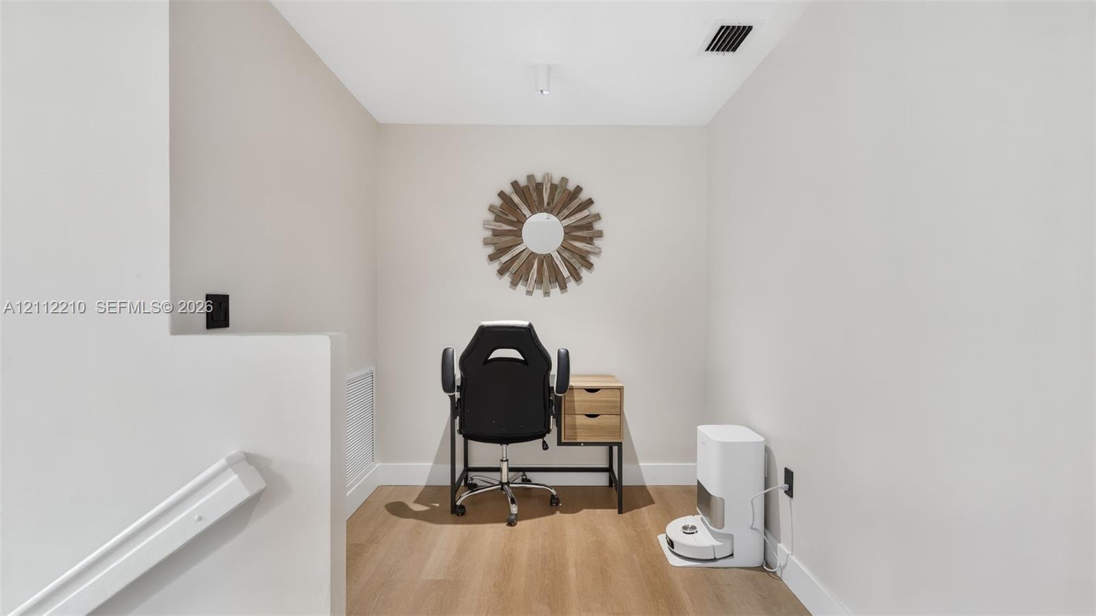 Neutral-toned interior space featuring wood-finish flooring and a partial-height wall