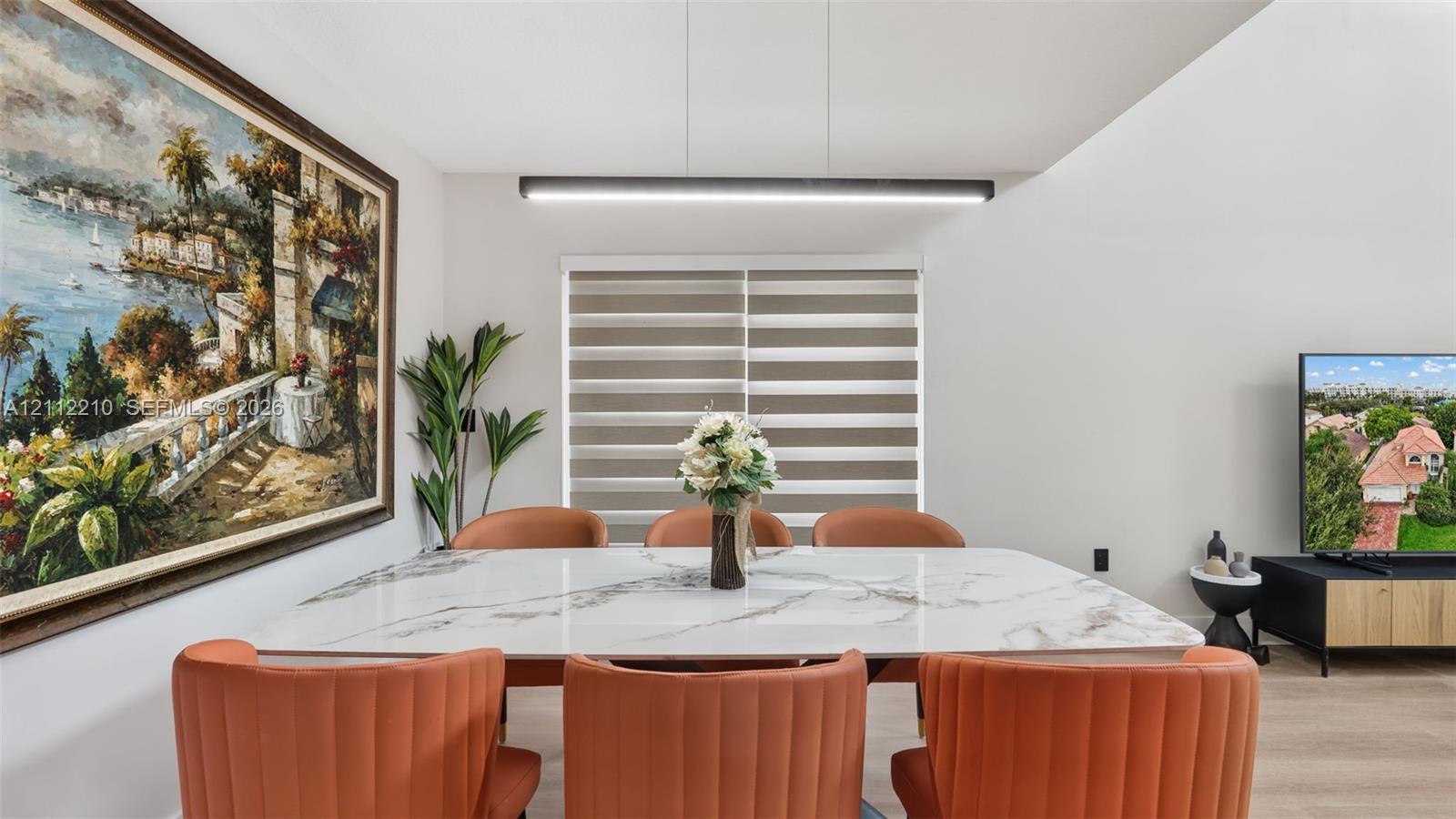 Dining area featuring neutral wall paint, wood-finish flooring, a contemporary linear pendant light, and horizontal window shades
