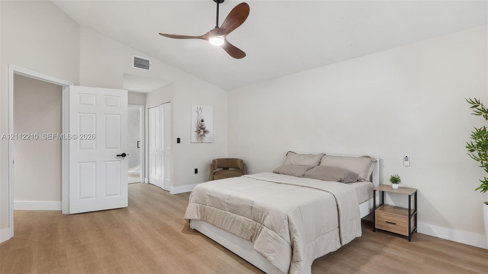 Vaulted ceilings featuring a multi-blade ceiling fan with integrated lighting and neutral-tone wood-finish flooring