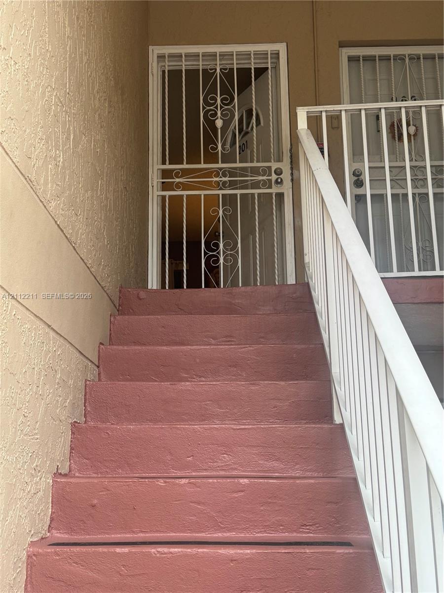 Stucco exterior staircase with painted concrete steps and metal railing featuring decorative security gates