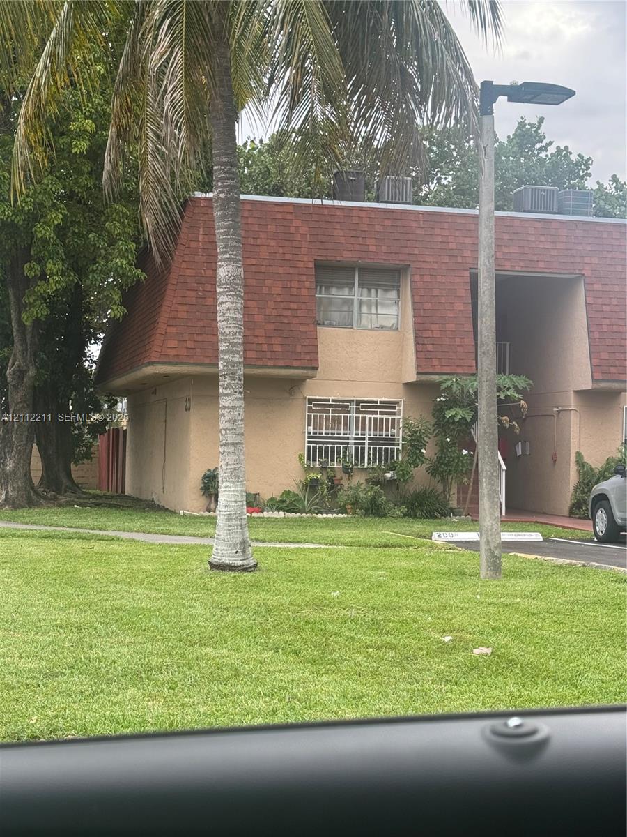 Two-story exterior featuring a mansard roof, stucco siding, and ground-level security bars