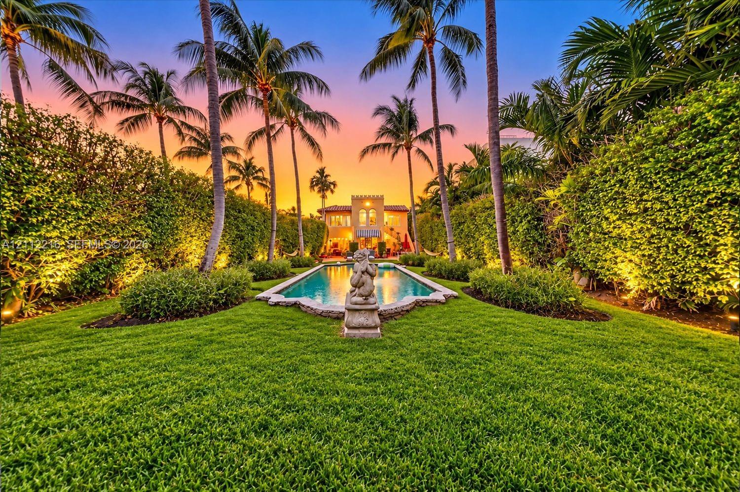 Expansive backyard featuring a rectangular swimming pool, stone sculpture, manicured lawn, and mature palm trees framed by high-density hedges Expansive backyard featuring a rectangular swimming pool, stone sculpture, manicured lawn, and mature palm trees framed by high-density hedges