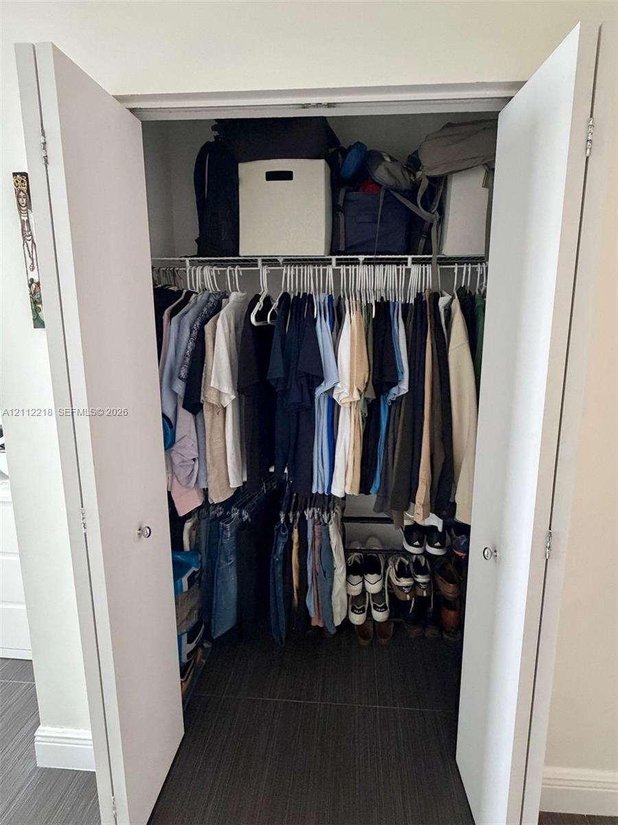Reach-in closet featuring dual white hinged doors and integrated wire shelving