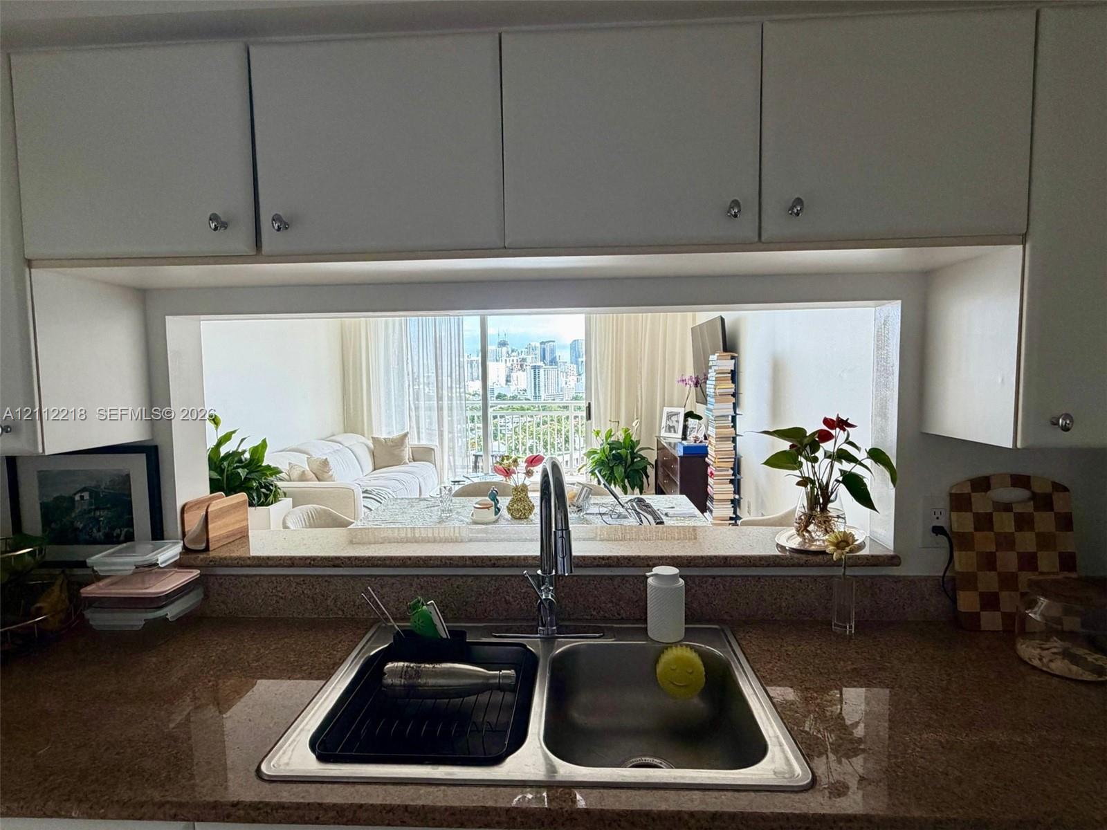 Kitchen featuring white upper cabinetry, stone-finish countertops, and an integrated stainless steel double-basin sink with a gooseneck faucet