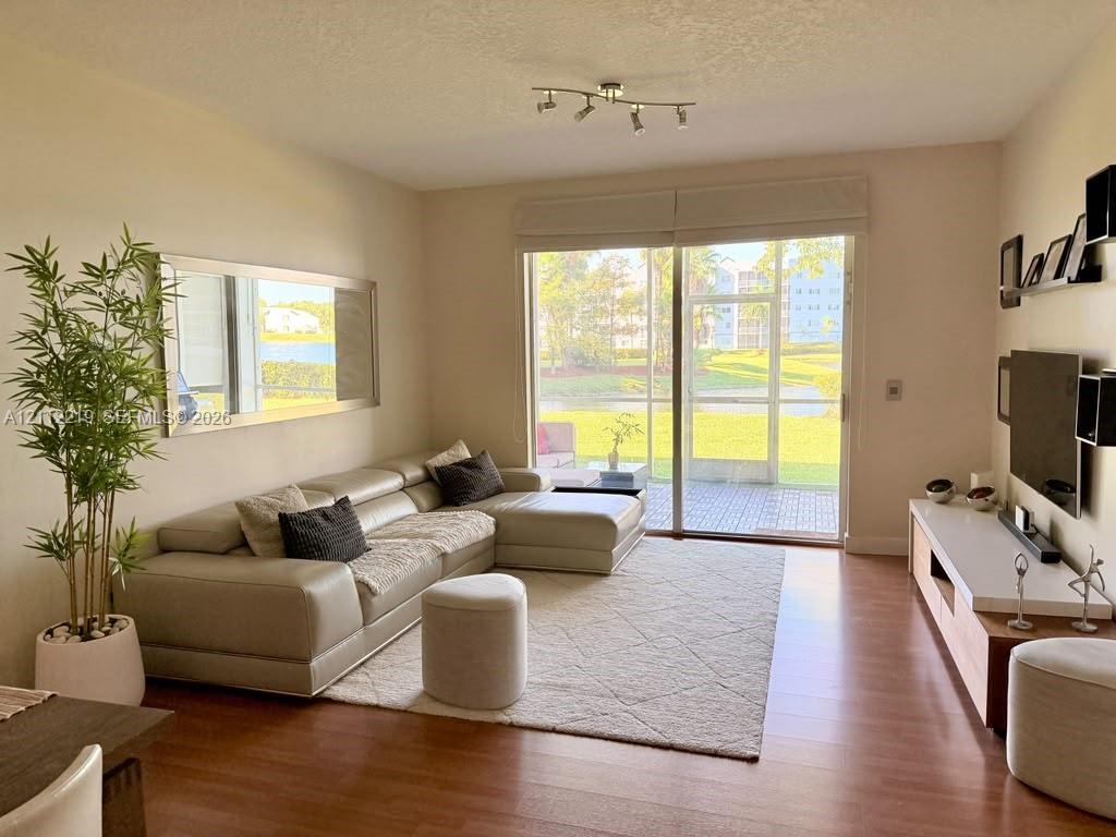 Living space featuring wood-finish flooring, sliding glass doors, built-in media shelving, and a track lighting fixture Living space featuring wood-finish flooring, sliding glass doors, built-in media shelving, and a track lighting fixture