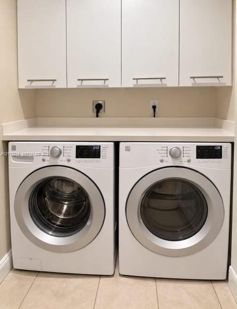 Laundry area featuring white cabinetry with brushed-metal pulls, solid-surface countertop, and ceramic tile flooring