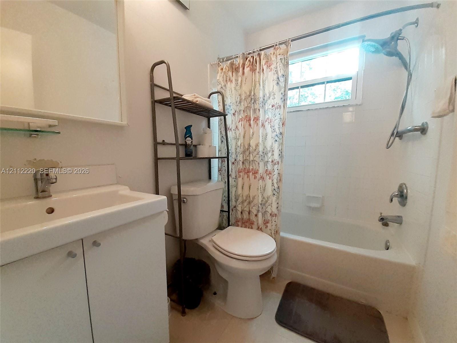Bathroom featuring a vanity with an integrated sink, polished chrome faucet, white tiled shower surround, and a single-handle shower system