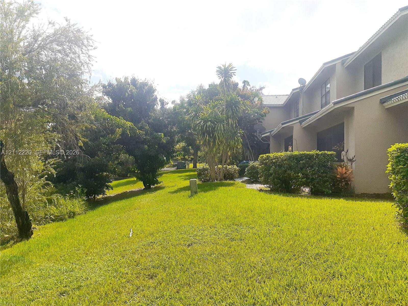 Stucco exterior featuring sloped rooflines, multi-level construction, mature landscaping, and an expansive lawn