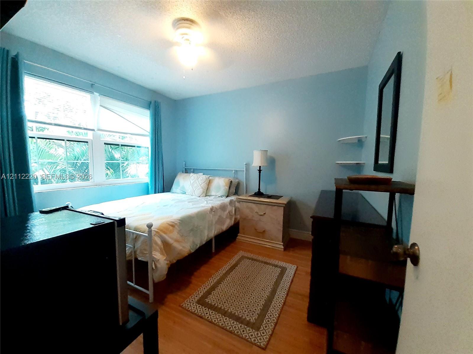 Bedroom featuring wood-finish flooring, dual-pane windows, and wall-mounted shelving
