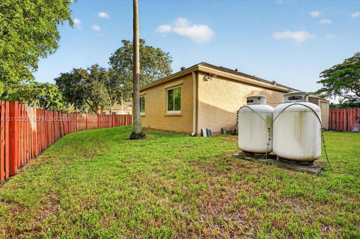 Stucco exterior with a grass-covered backyard and perimeter fencing