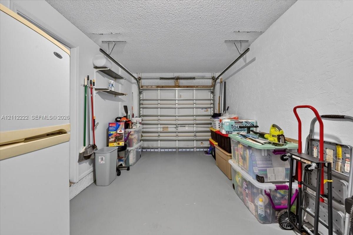 Enclosed garage featuring painted concrete flooring, a paneled sectional door, and built-in wall-mounted shelving