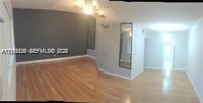 Interior space featuring wood-finish flooring, a dark-toned accent wall, and a full-length wall-mounted mirror