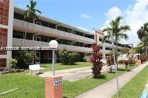 Multi-story exterior featuring decorative concrete latticework, covered balconies, brick-accented pillars, and landscaped grounds with mature palm trees
