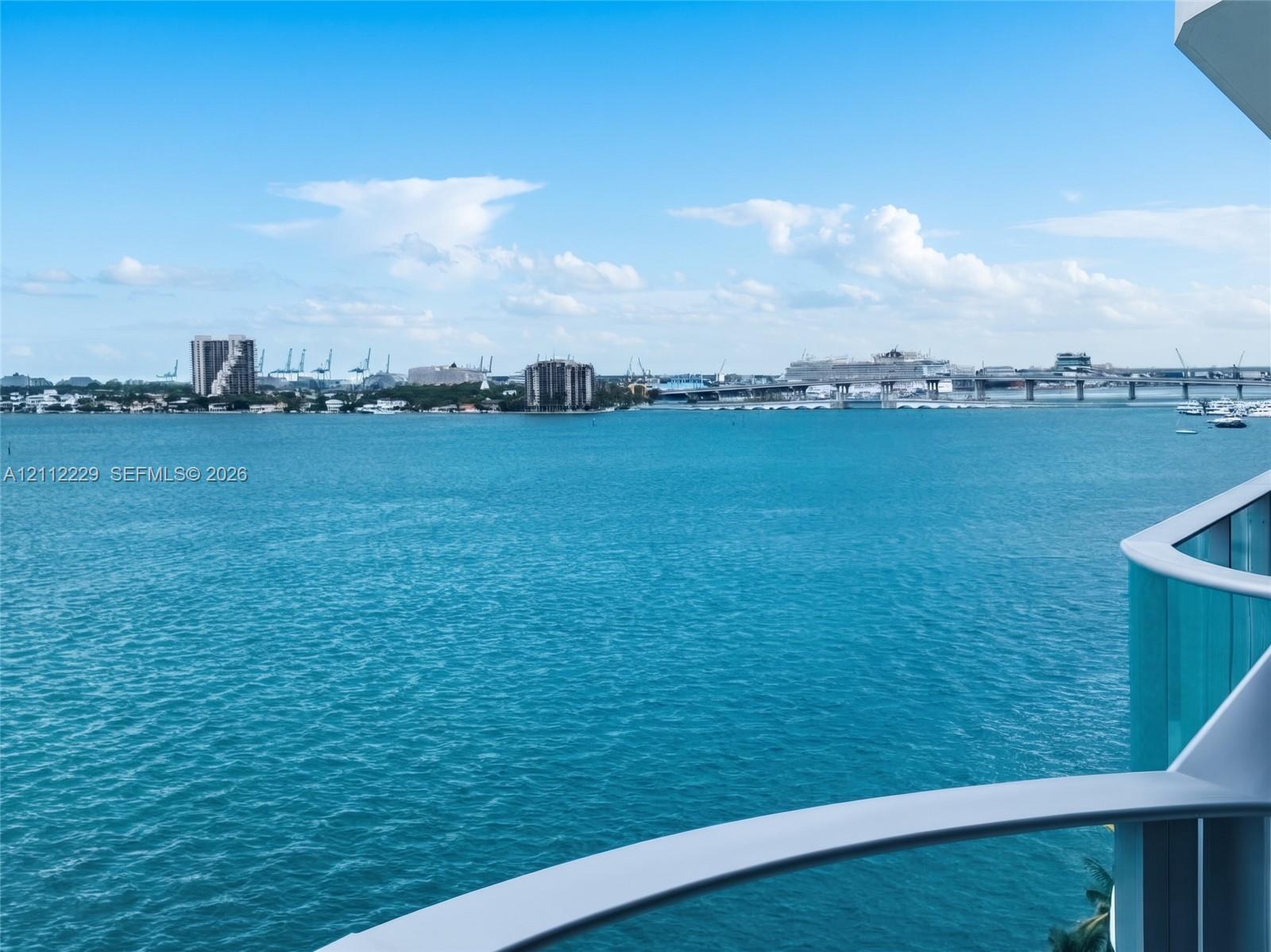 Balcony featuring a glass railing and expansive water horizon