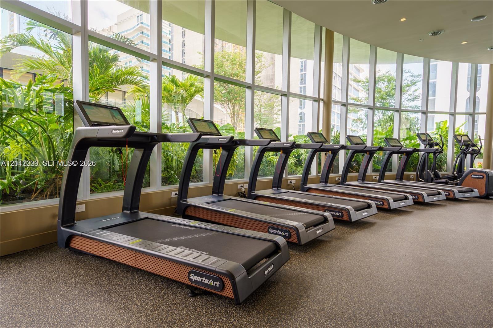 Fitness center featuring floor-to-ceiling windows, professional-grade treadmills, and rubberized flooring