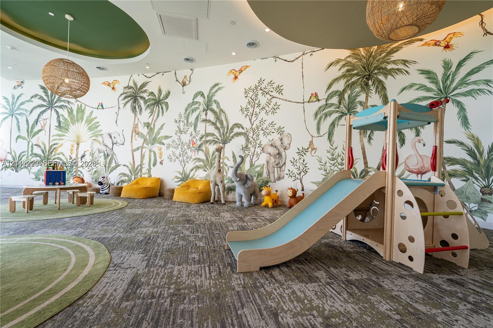 Common area featuring a mural-accented wall, patterned carpeting, recessed circular ceiling coves, and textured woven pendant lighting