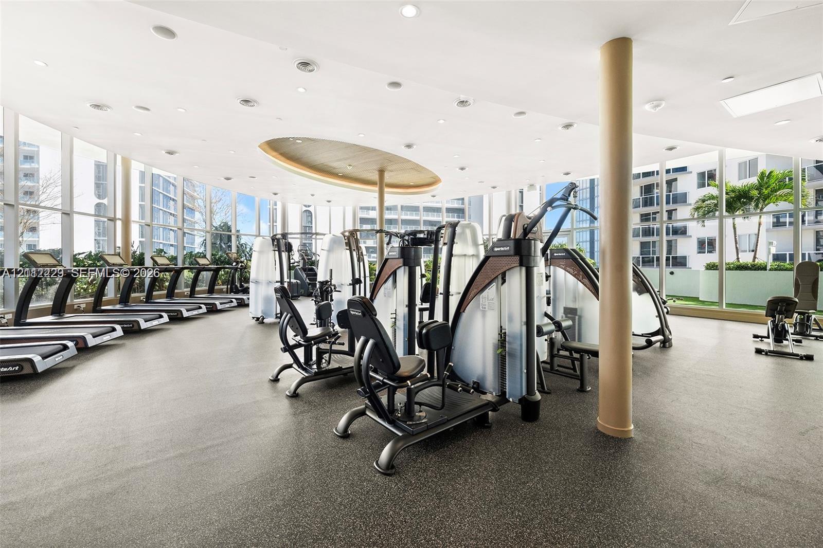 Fitness center featuring floor-to-ceiling windows, recessed lighting, architectural ceiling detail, and rubberized flooring