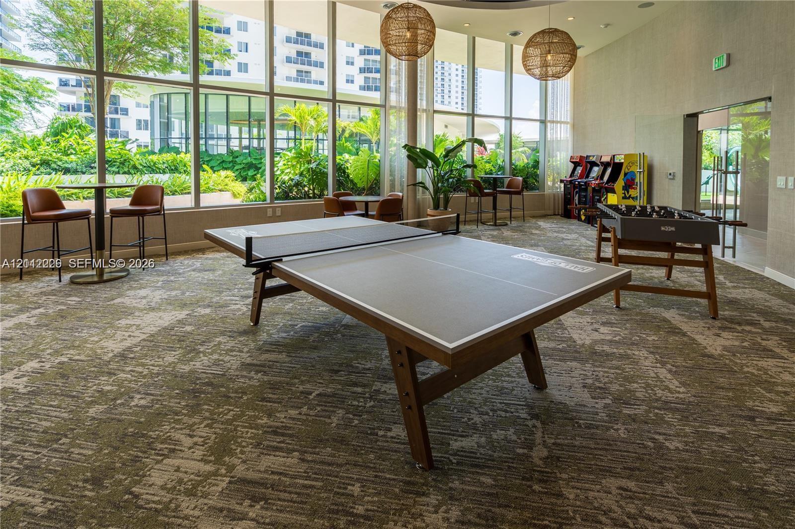 Recreational space featuring floor-to-ceiling windows, patterned carpeting, and spherical pendant lighting