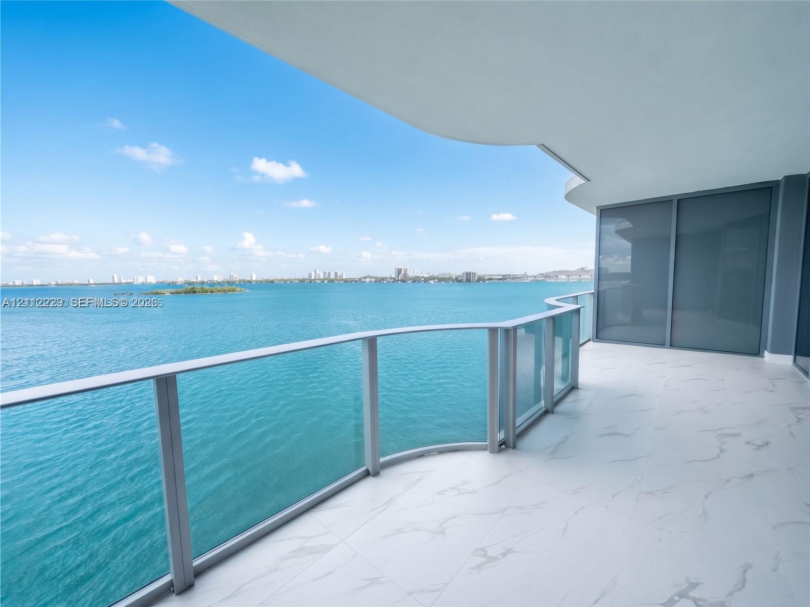 Expansive covered balcony featuring large-format tile flooring and a curved glass-panel railing