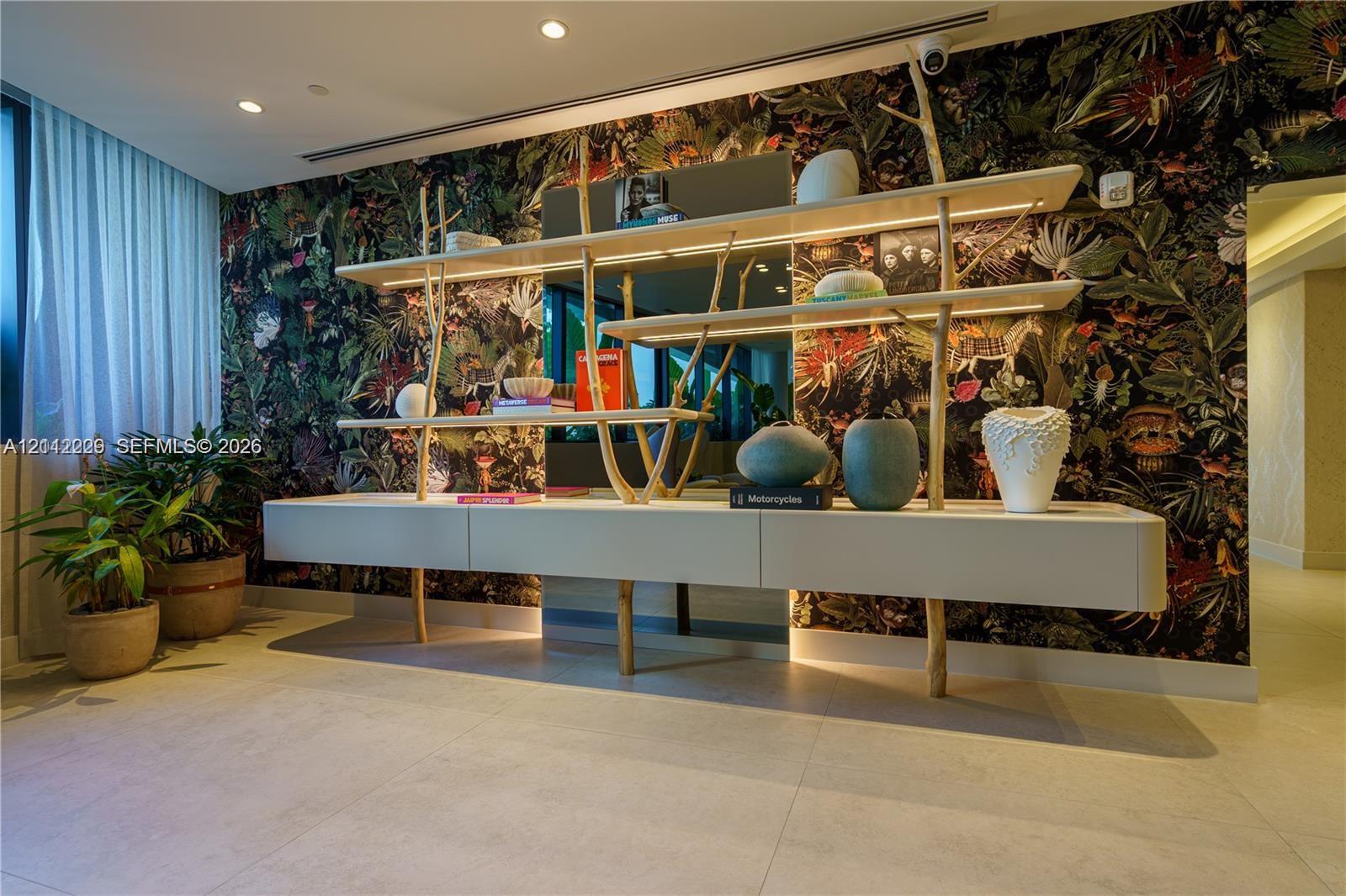 Custom built-in wall unit featuring matte-finish cabinetry, integrated linear LED shelf lighting, and sculptural branch-style supports, set against a bold botanical-patterned accent wall with tile flooring