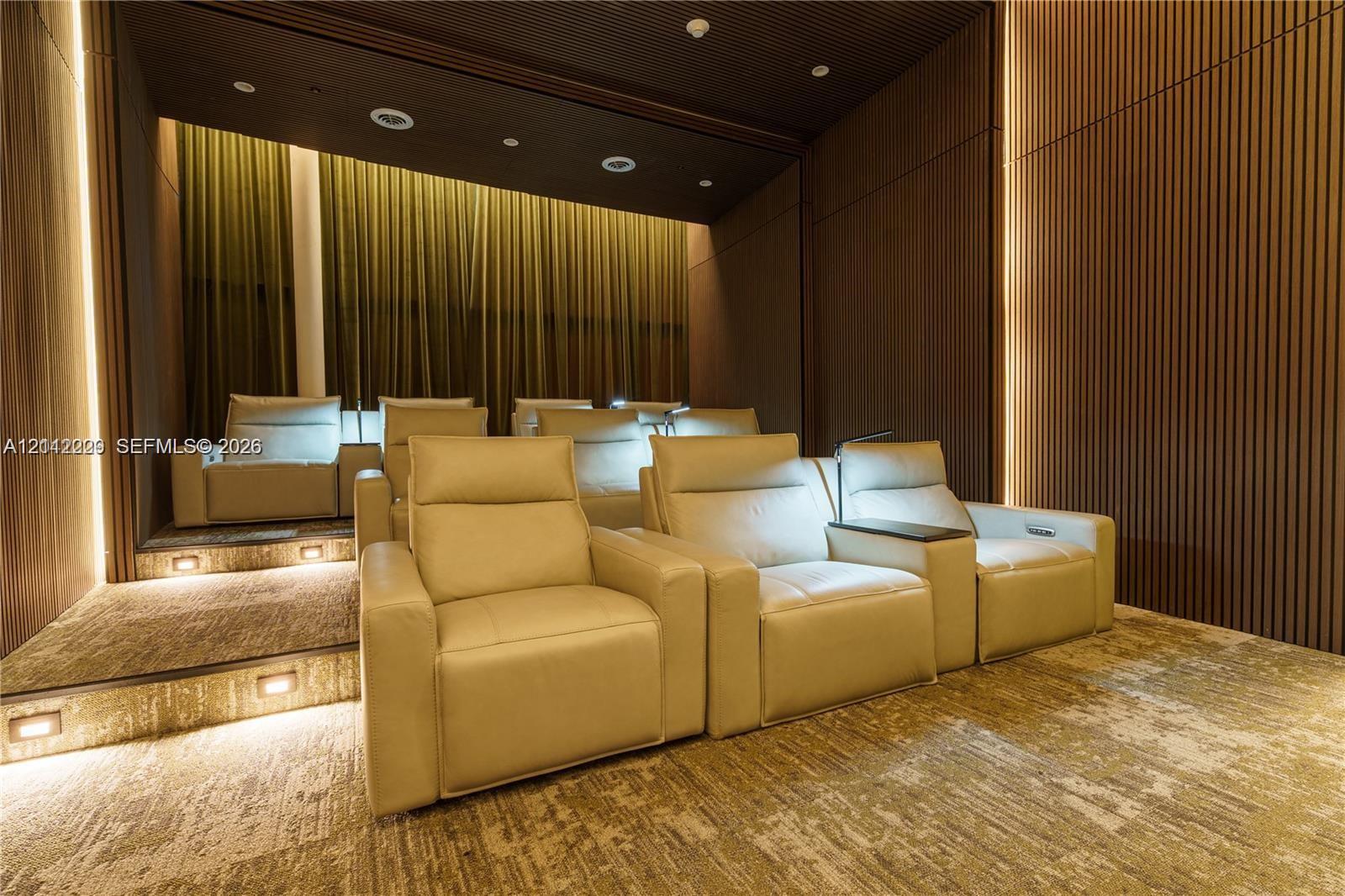 Tiered theater room featuring custom vertical wood-slat wall paneling, integrated LED accent lighting, recessed ceiling lights, and integrated stair lighting