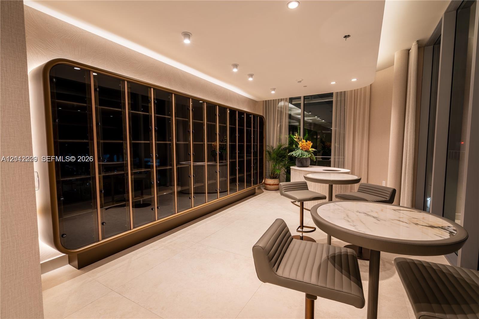 Custom floor-to-ceiling built-in display cabinetry with metallic trim, recessed perimeter lighting, porcelain tile flooring, and integrated ceiling spotlights