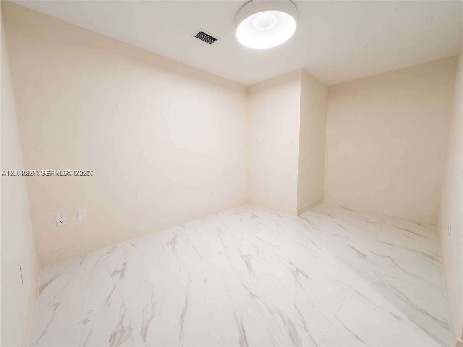 Den featuring large-format white stone-finish tile flooring and a neutral color palette, illuminated by a contemporary circular flush-mount ceiling light
