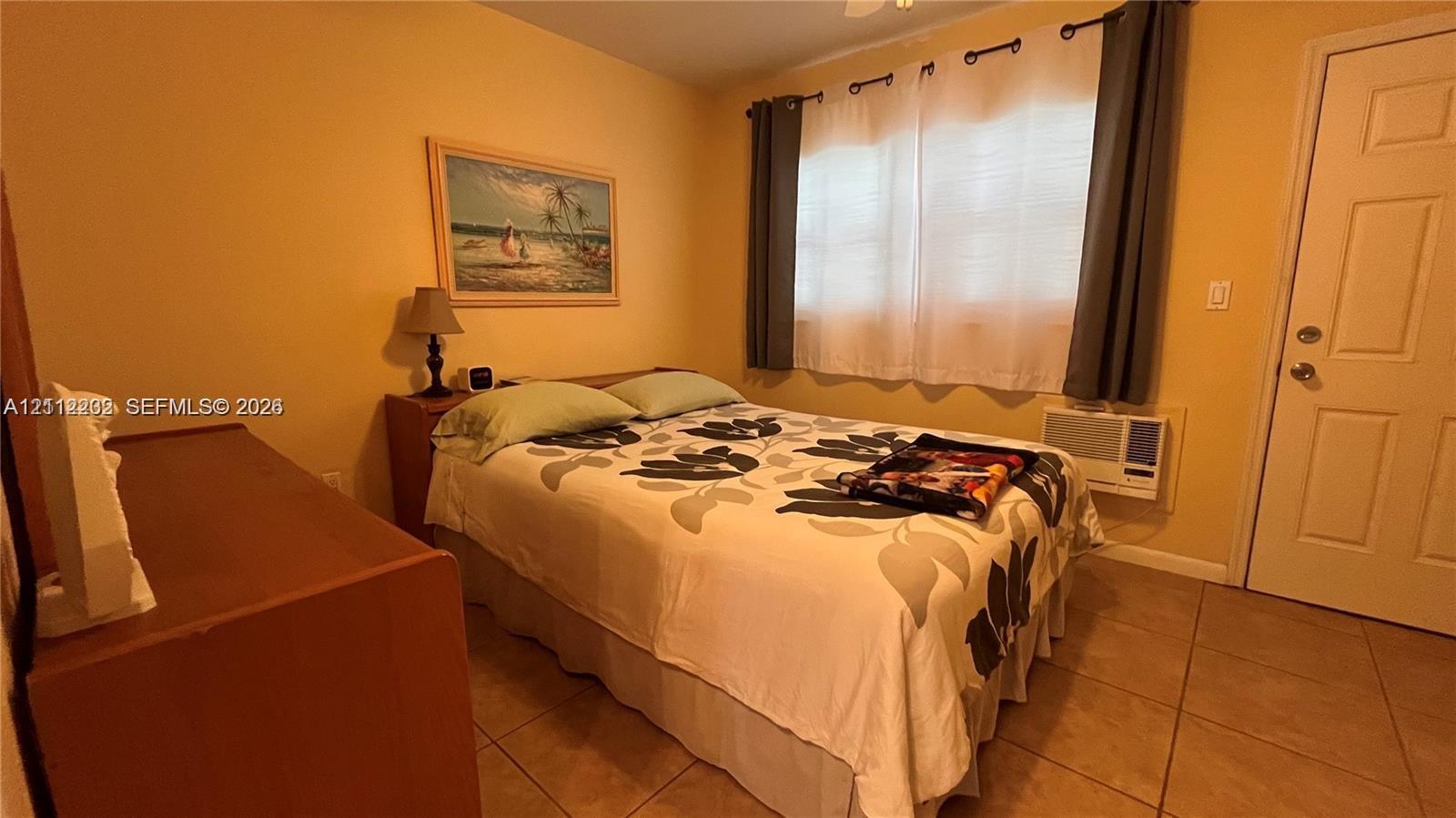 Room featuring tile flooring, a wall-mounted cooling unit, and a paneled exterior door
