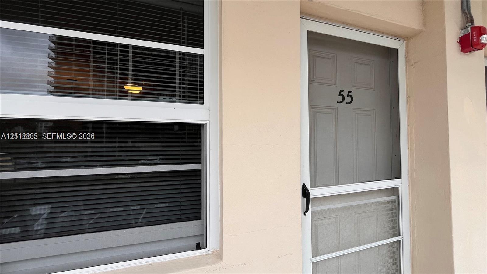Exterior entry featuring a white-framed storm door and a window with integrated horizontal blinds