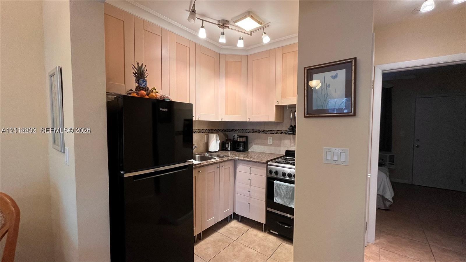 Kitchen featuring light-toned cabinetry, stone-finish countertops, tile flooring, and track lighting