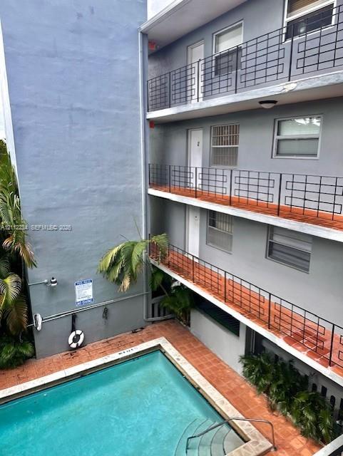 Exterior featuring a swimming pool with integrated stairs, terracotta-tiled patio, and multi-level balconies with decorative metal railings