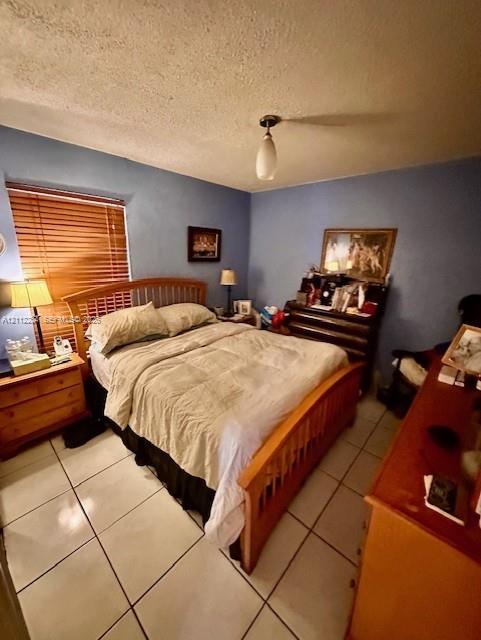 Room with light-colored tile flooring, neutral wall tones, window featuring horizontal blinds, and a centered pendant light fixture